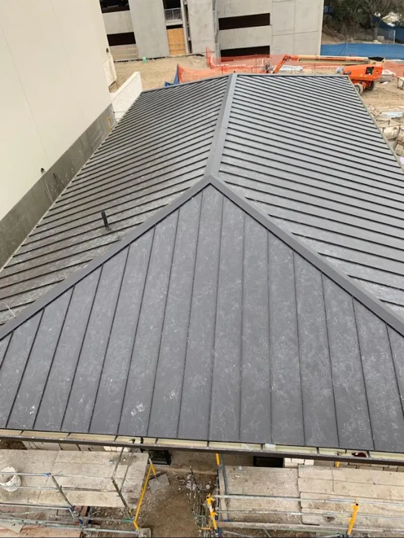 Commercial metal roof construction with crane equipment in Mendon